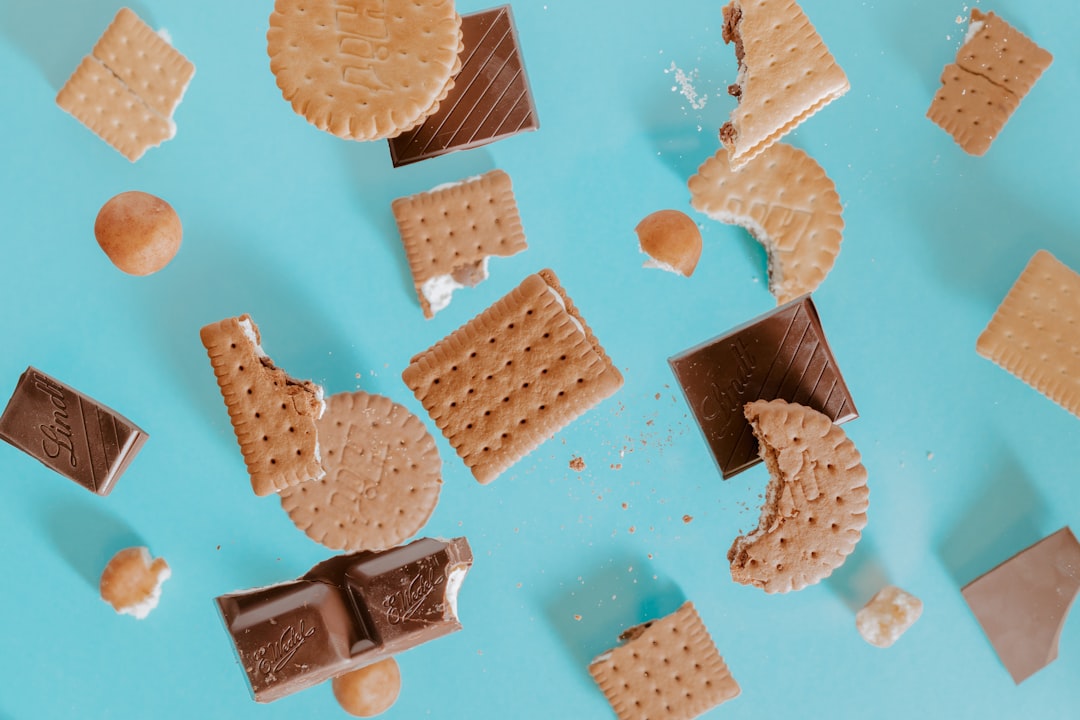 Broken biscuits and squares of chocolate scattered on a pale blue background